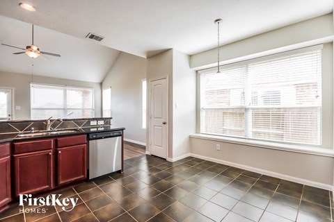 A kitchen with a black counter top and red cabinets.
