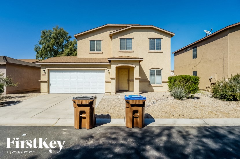A house with a garage door and two trash cans in front.