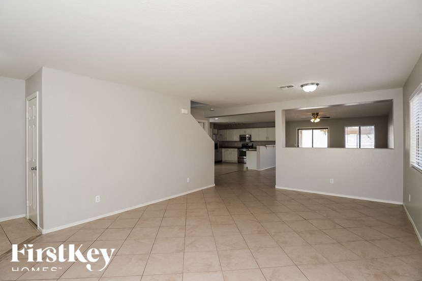 A spacious empty room with a kitchen area in the background.