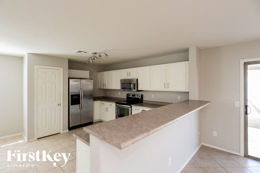 A kitchen with a refrigerator, microwave, oven, and cabinets.
