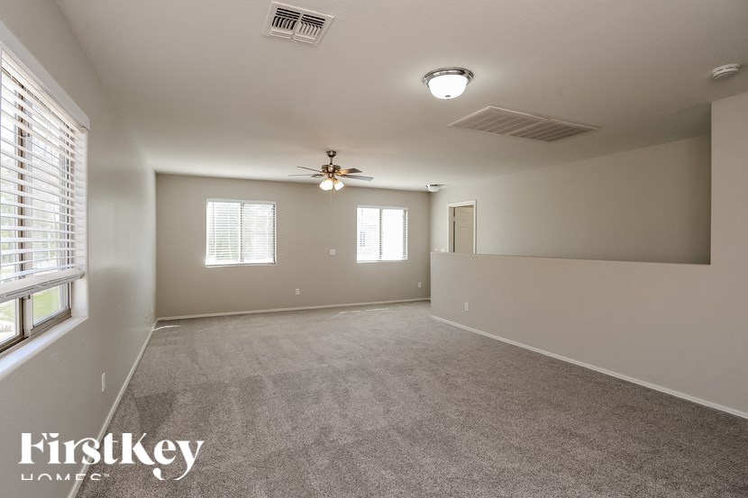 A spacious room with a ceiling fan and two windows.