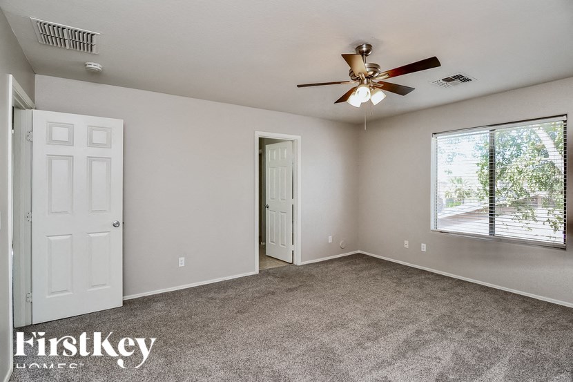 A spacious room with a ceiling fan and a window with blinds.