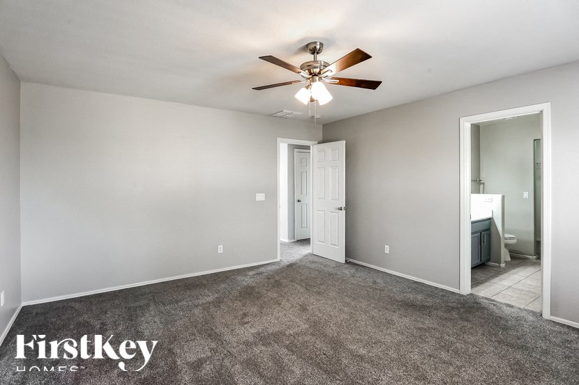 A spacious room with a ceiling fan and a door leading to another room.