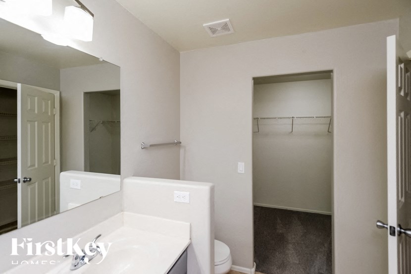 A white bathroom with a toilet, sink, and a walk-in shower.