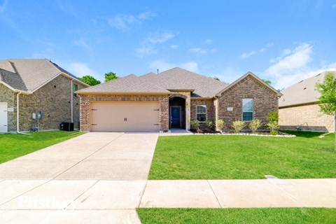 a brick house with a garage and a lawn