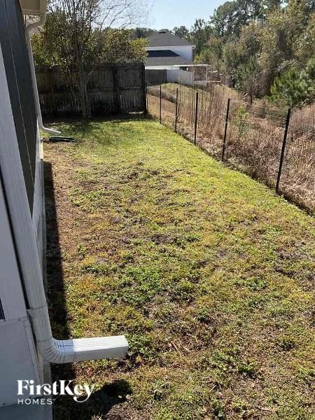 A backyard with a fence and a grassy area.