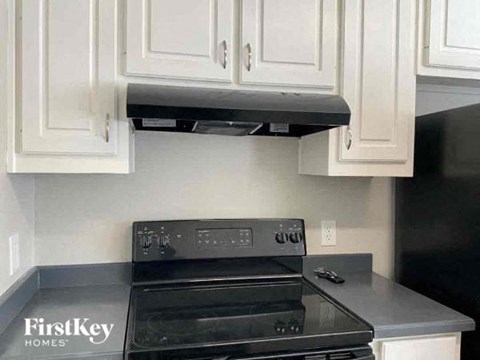 A black stove top oven with a stainless steel finish is installed in a kitchen with white cabinetry.