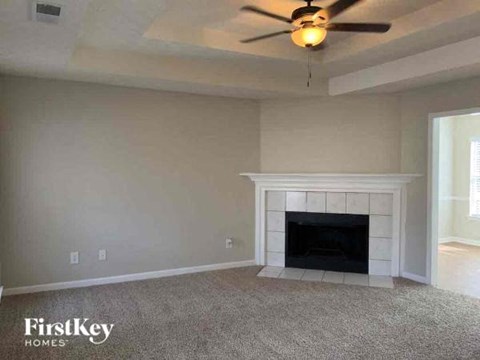 A living room with a fireplace and a ceiling fan.
