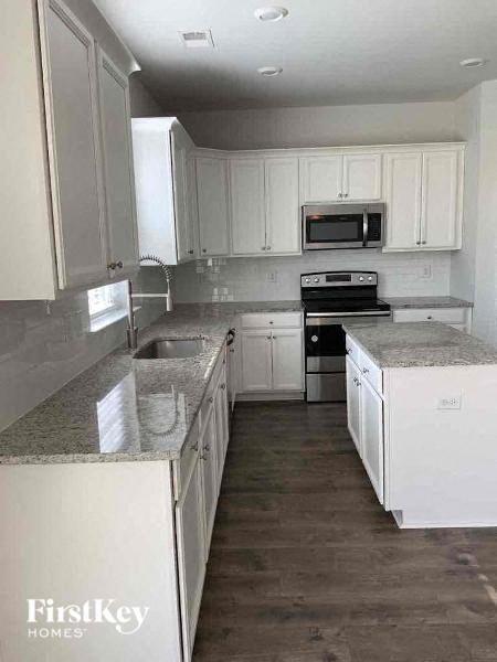A kitchen with white cabinets and a granite counter top.