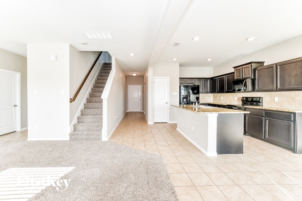 an open kitchen and living room with a staircase