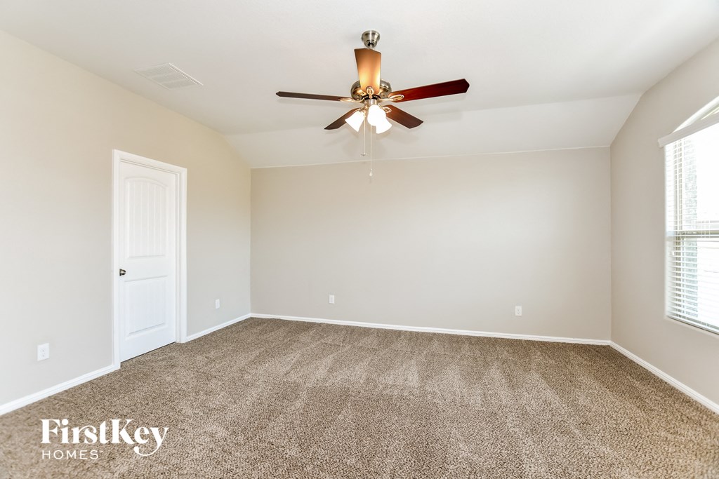the spacious living room with ceiling fan and carpet