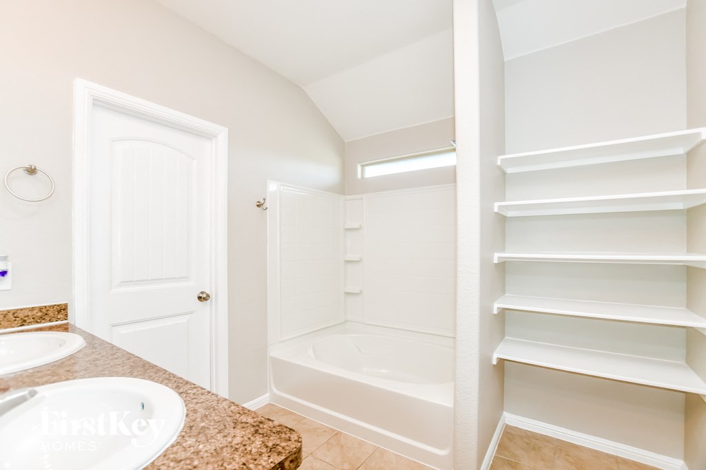 a bathroom with a sink and a tub and a closet