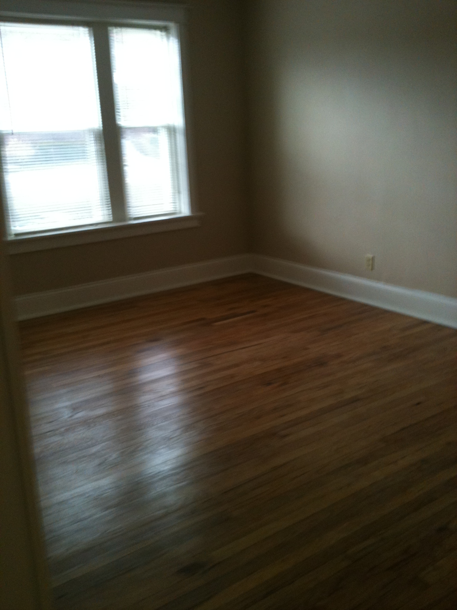 A room with a window and wooden floors.