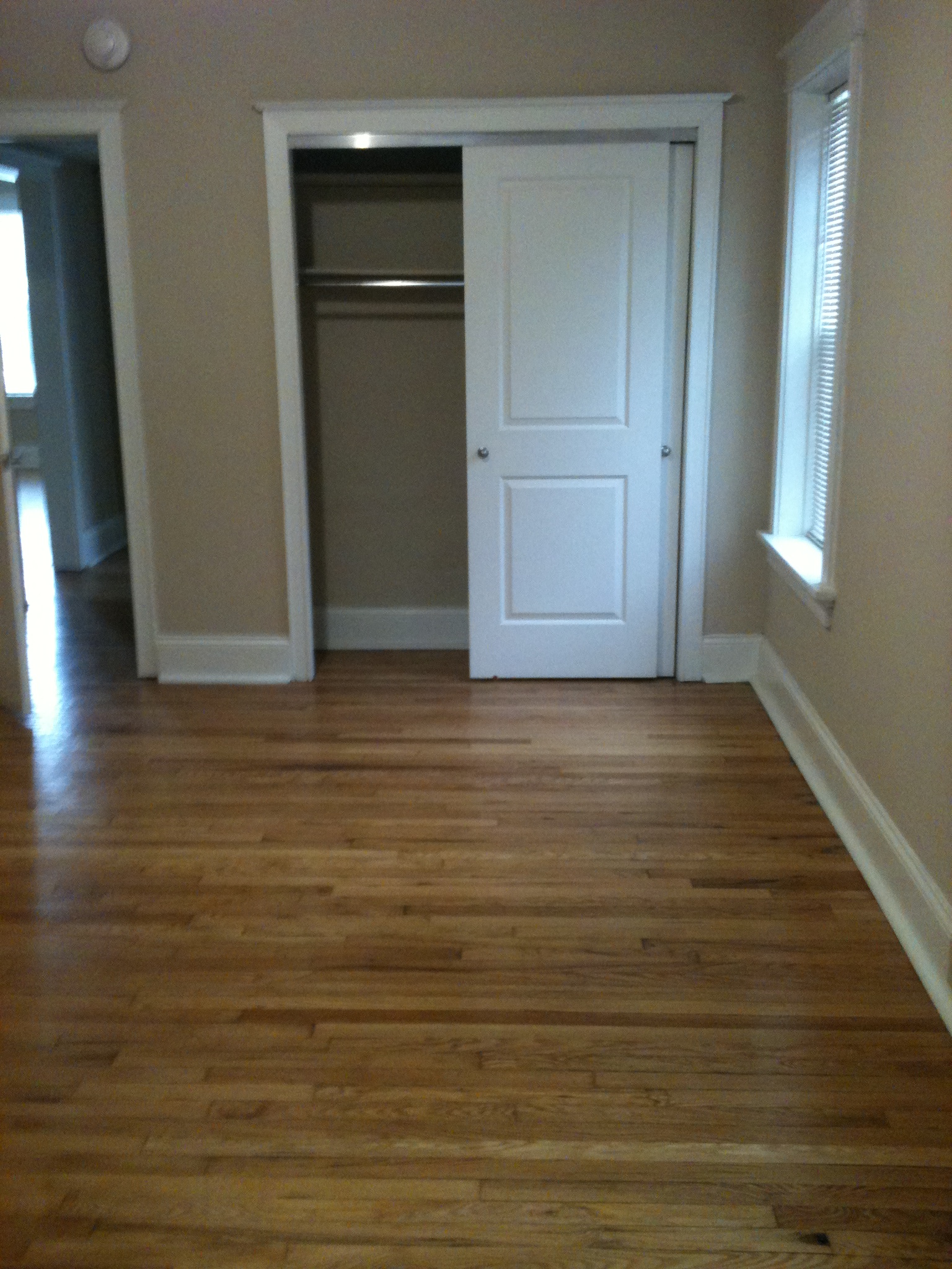 A room with a white door and a wooden floor.