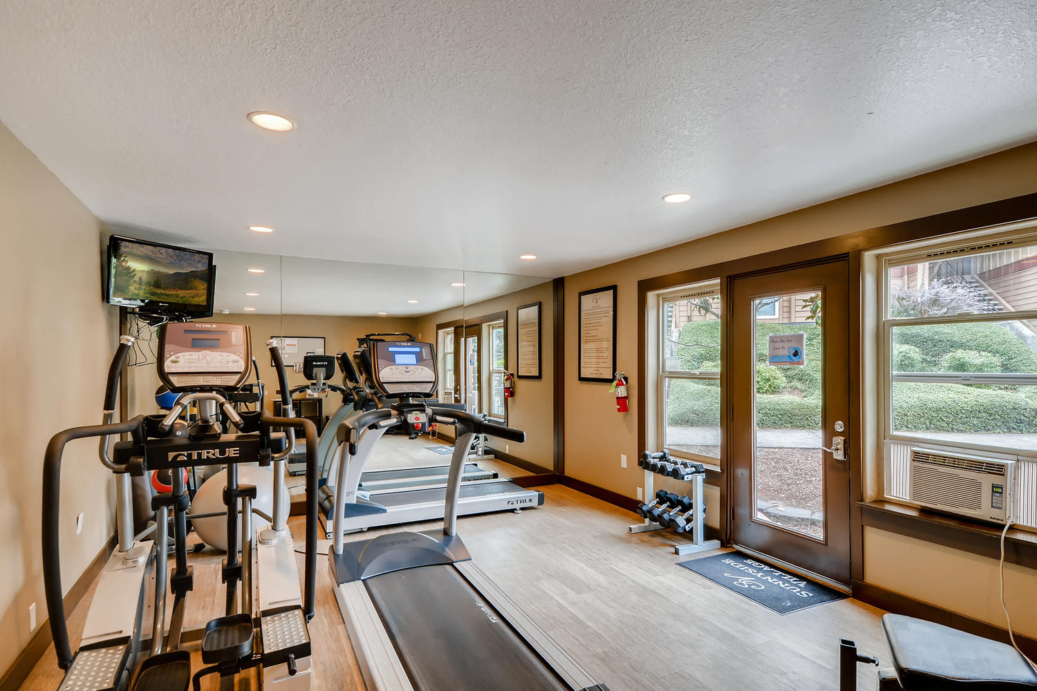 Apartments For Rent In Happy Valley, OR - Sunnyside Village - Fitness Center With Cardio Machines, Free Weights, and Full Body Mirror