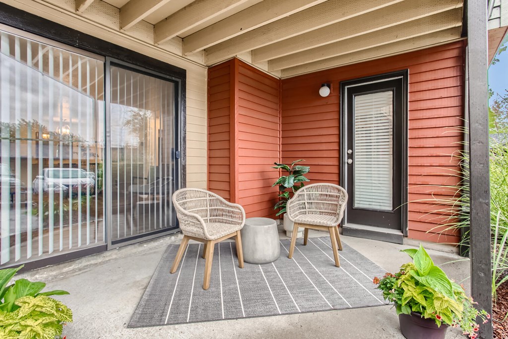 a patio with two chairs and a table in front of a door