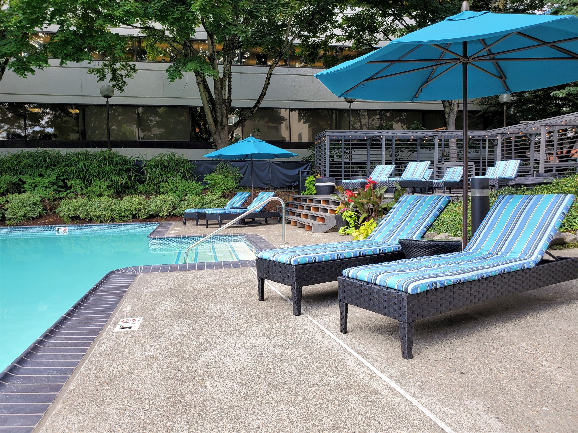 a swimming pool with lounge chairs and umbrellas next to a hotel pool
