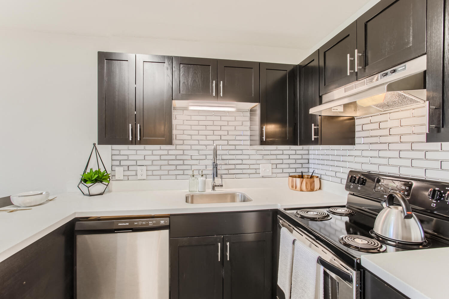 Apartments In Downtown Portland For Rent - Kitchen With New Cabinetry, Corian Counters, Modern Fixures, Dishwasher, Tile Backsplash, And Electric Stovetop.