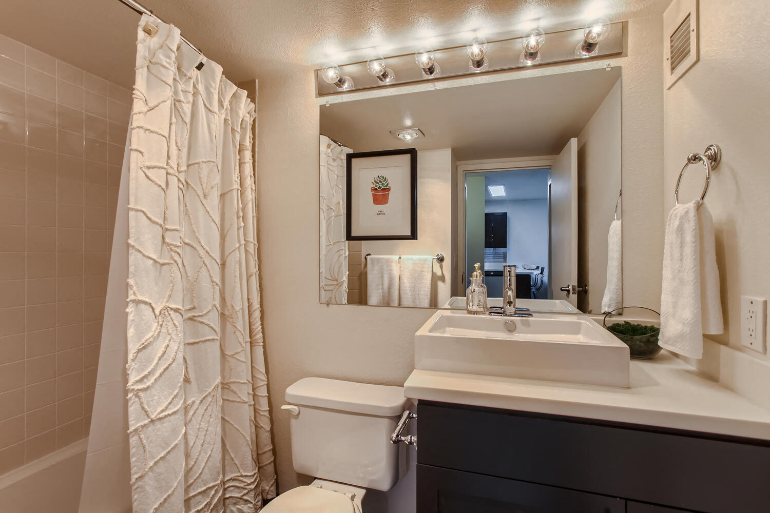 Downtown Portland Apartments For Rent - Bathroom With Modern Fixtures, Large Vanity Mirror With Lighting, Toilet, And A Shower And Tub Combo.