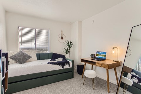 a bedroom with a bed and a desk with a mirror