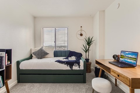 a bedroom with a bed and a desk with a laptop