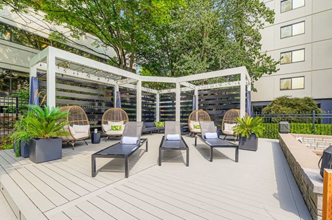 A patio with a white pergola and black furniture.