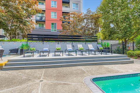 A pool and sunbeds in front of a red building.