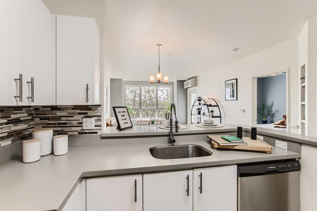 a white kitchen with a sink and a window