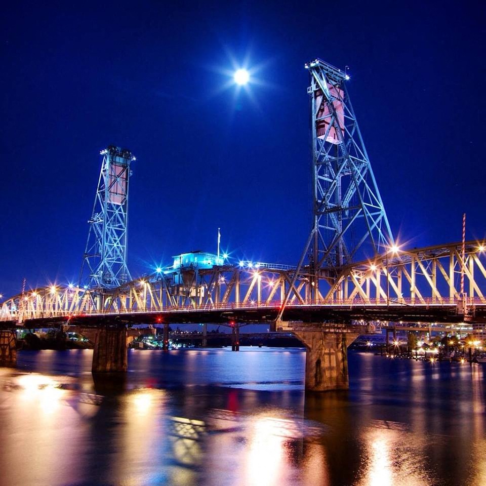 a bridge at night with the moon over the water
