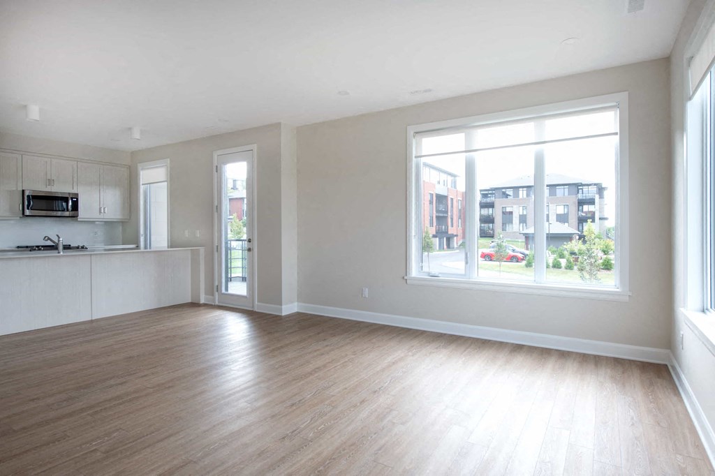 an empty living room with a large window and wood floors