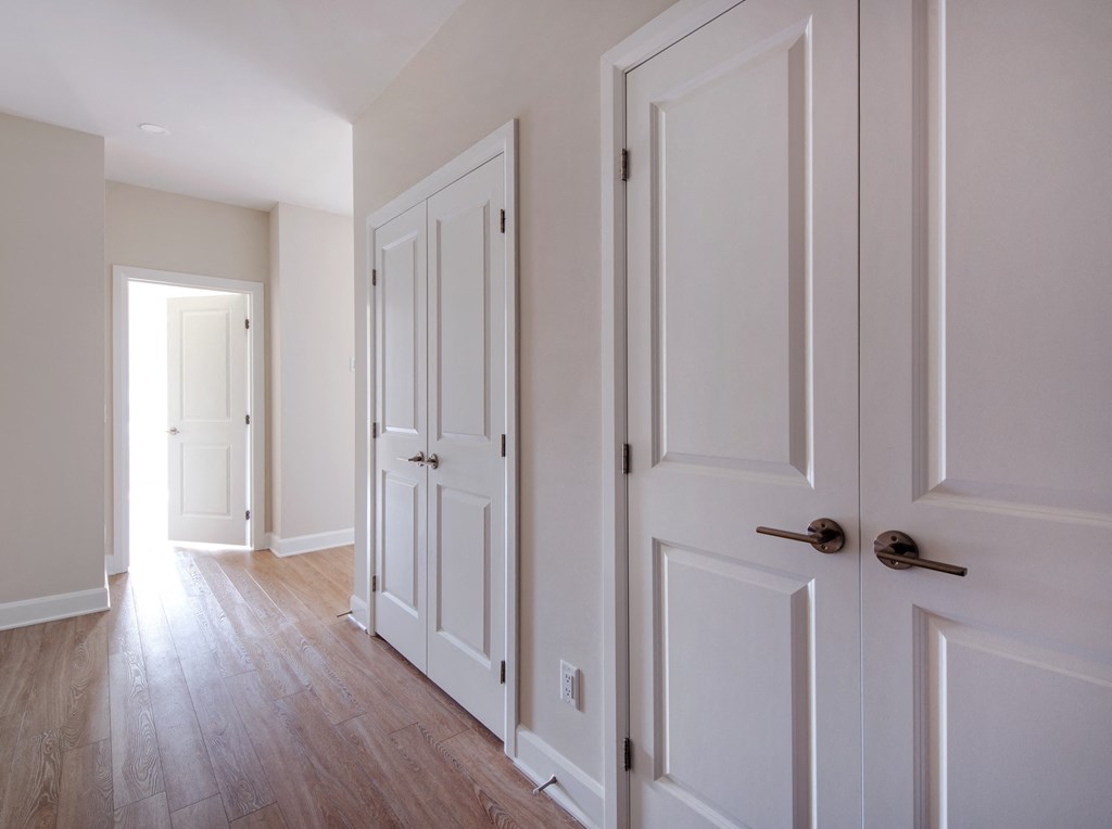an empty hallway with white doors and wood floors