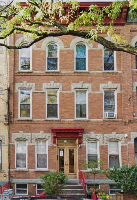 A red brick building with a wooden door and windows.