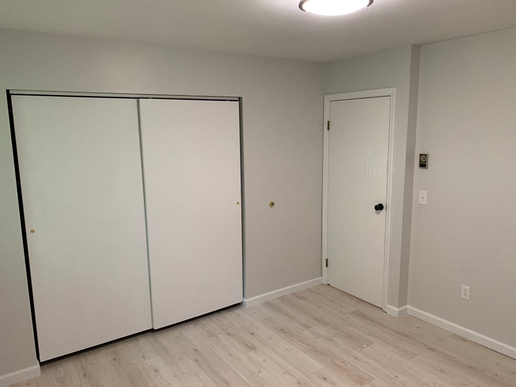 a bedroom with two closets and a wood floor and white walls