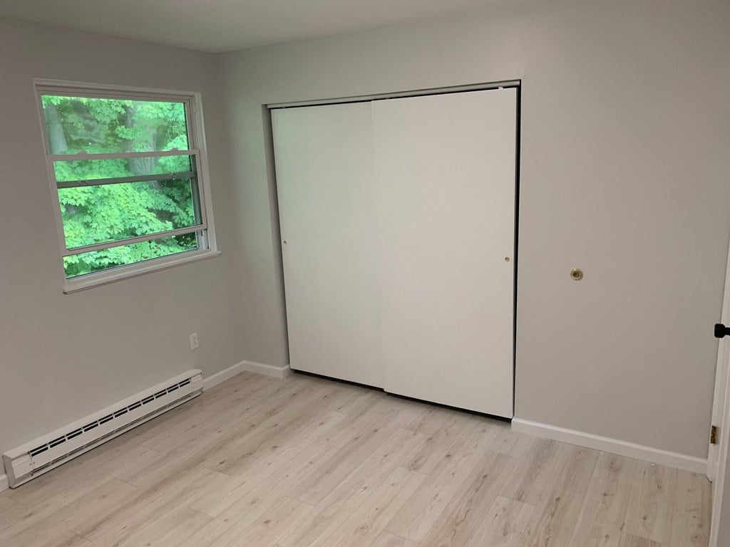a bedroom with a closet and a window and a wood floor
