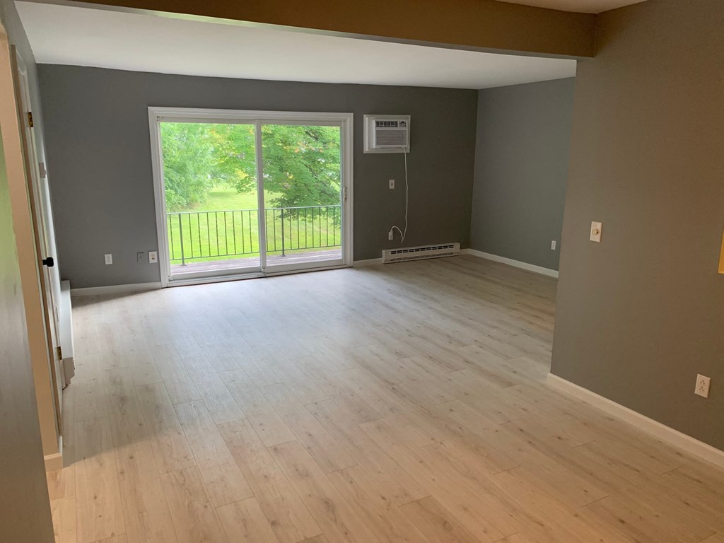 an empty living room with wood floors and a sliding glass door