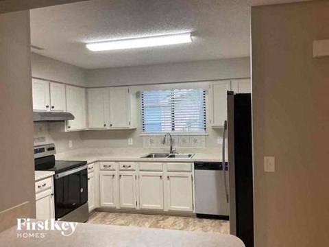 an empty kitchen with white cabinets and black appliances