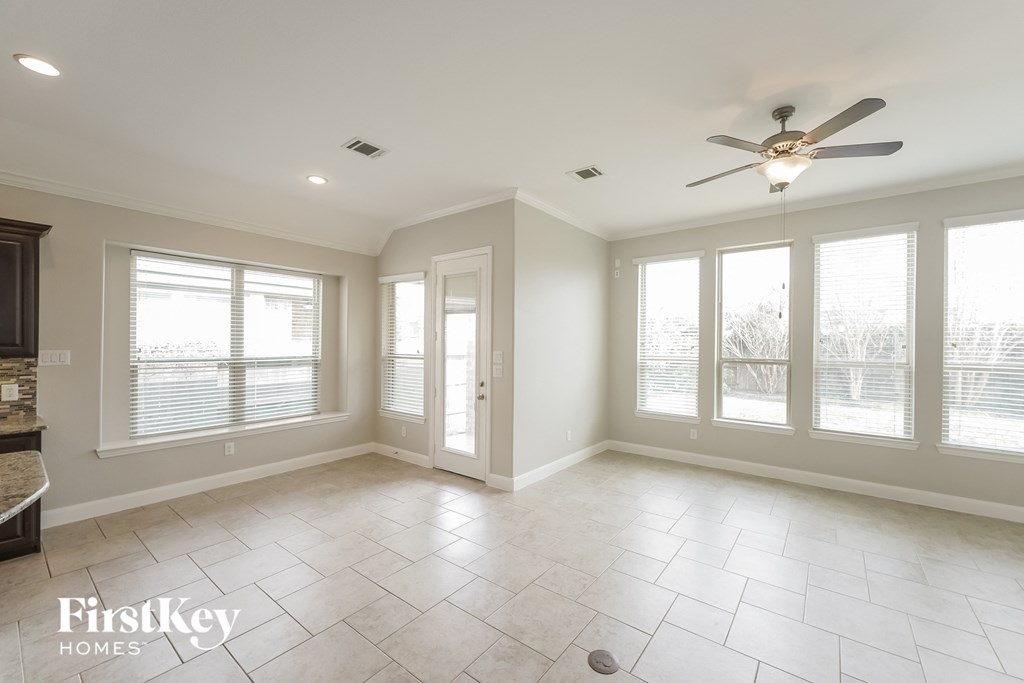 an empty living room with windows and a ceiling fan