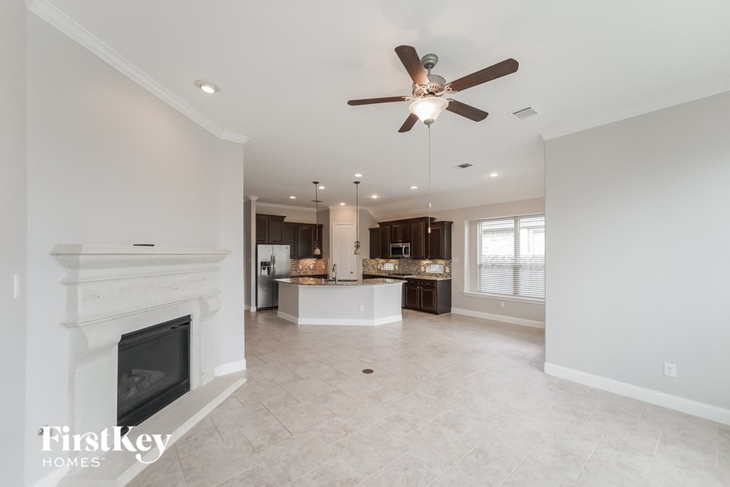 a kitchen and living room with a fireplace and a ceiling fan