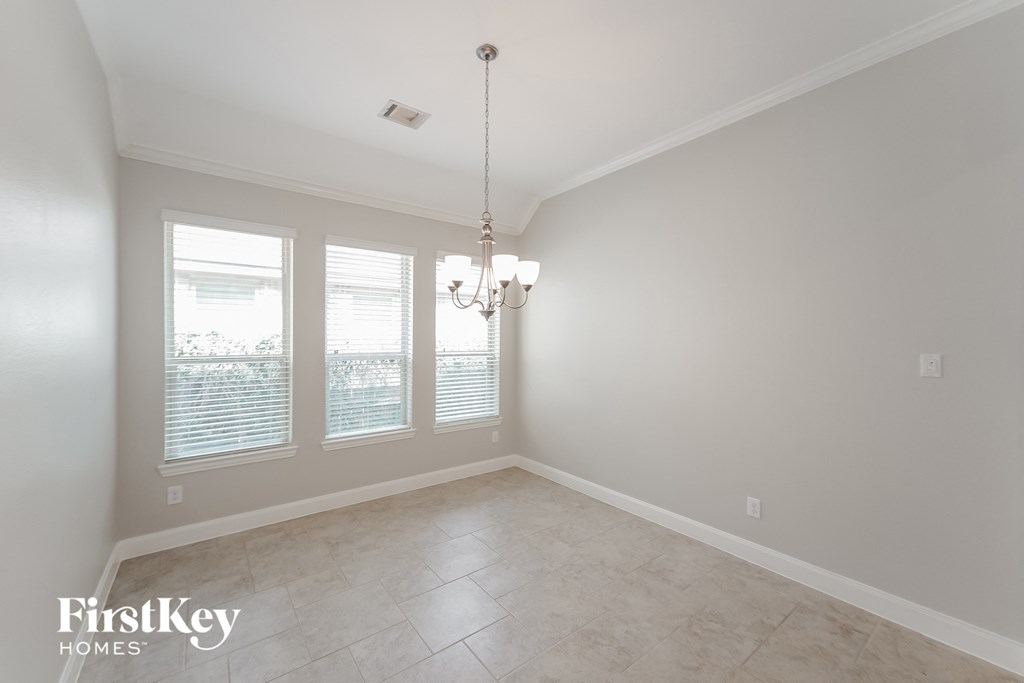 an empty dining room with three windows and a chandelier