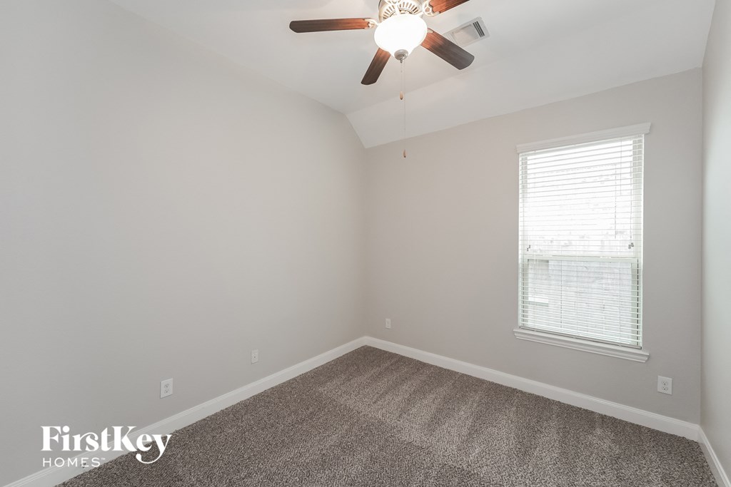 an empty room with a ceiling fan and a window