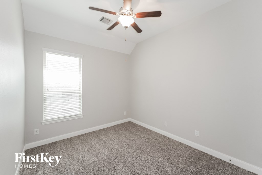 an empty room with a ceiling fan and a window