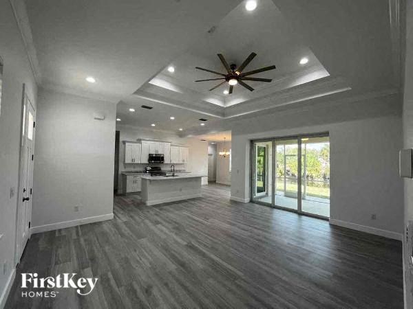 a empty living room with a ceiling fan and a kitchen