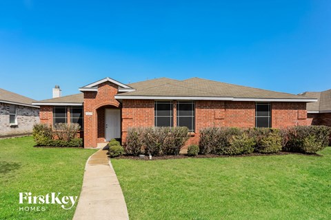A brick house with a white door and a small front yard.