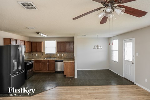A kitchen with a black fridge and wooden cabinets.
