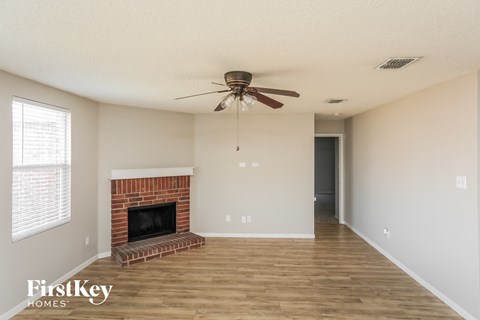 A living room with a fireplace and a ceiling fan.