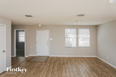 A room with wooden floors and white walls, with a door and a window.
