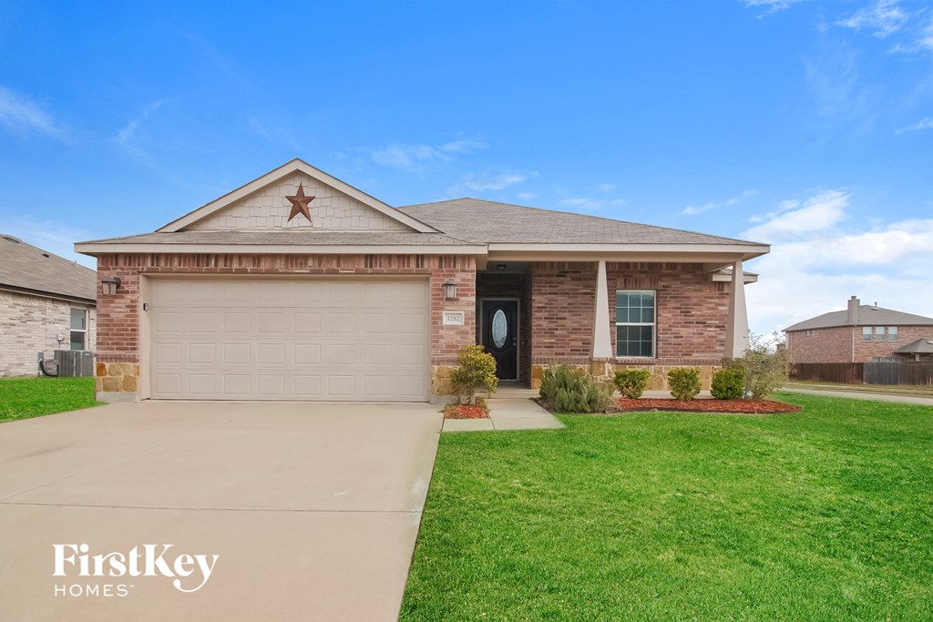 a brick house with a garage door and a lawn
