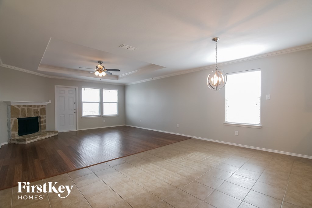 an empty living room with a fireplace and a ceiling fan