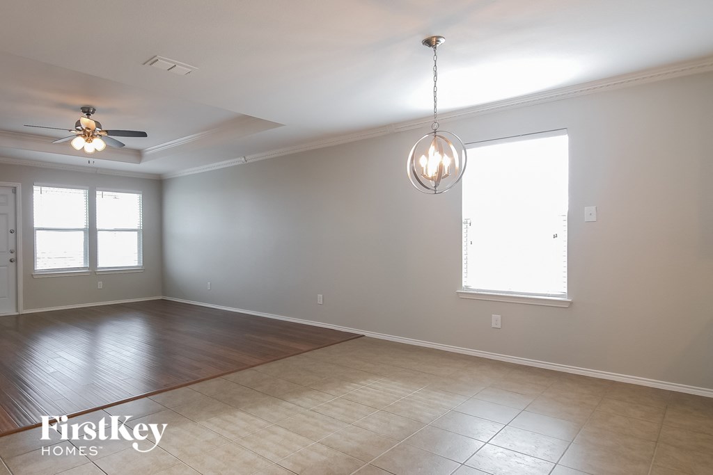 an empty living room with a ceiling fan and a window