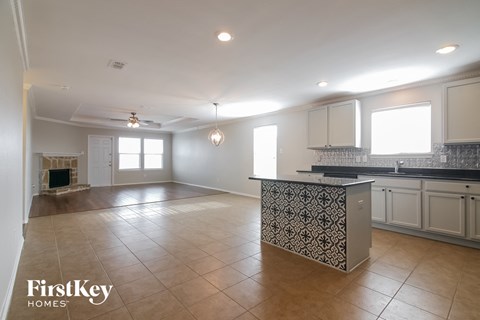 an open kitchen and living room with white cabinets and tile flooring